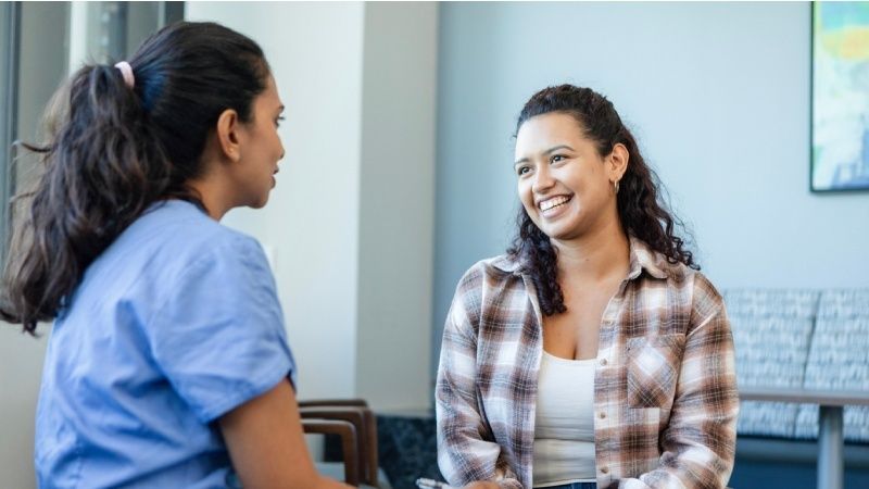 Healthcare worker and smiling patient having a face-to-face conversation